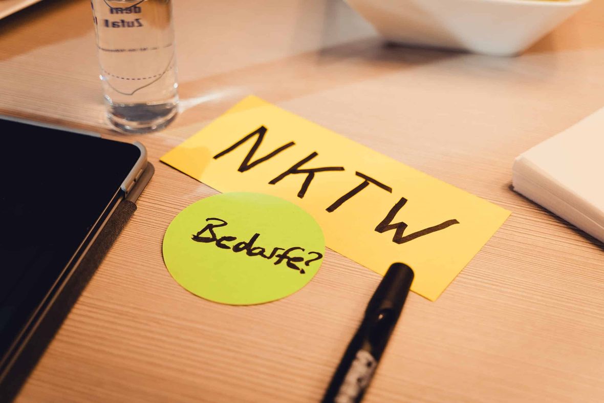 Moderationskarten mit den Aufschriften NKTW und Bedarfe? auf einem Tisch neben Tablet und Stift