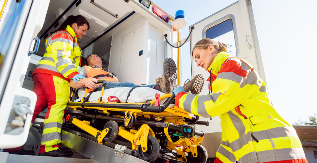 Sanitäter in Uniform setzen verletzten Mann auf Trage im Krankenwagen